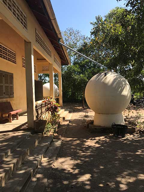 A white water tank installed beside a house