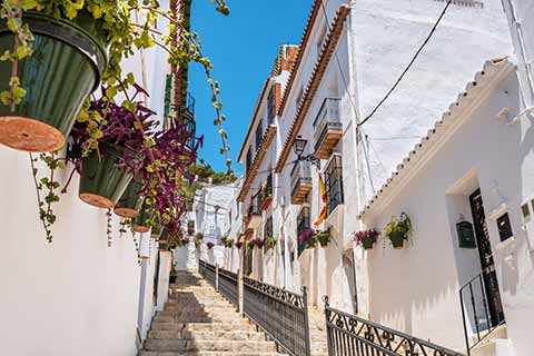 Stairs upwards for pedestrians, blue sky and white houses with flower boxes