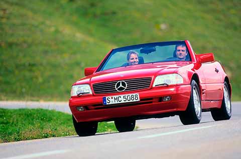 Mercedes Benz SL fourth generation in red, two people sitting inside enjoying a ride with open top