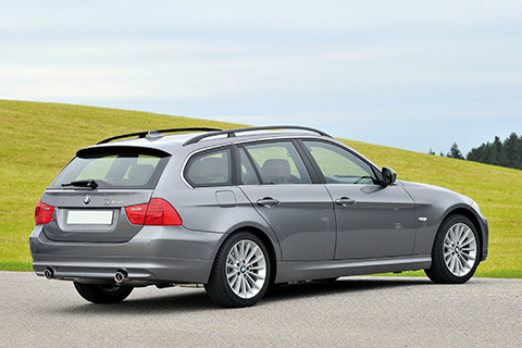 Grey BMW335d parking in front of a green hill