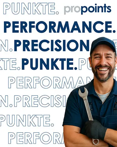 A mechanic holding a socket wrench smiling into the camera, left to him are different words in German and English visible