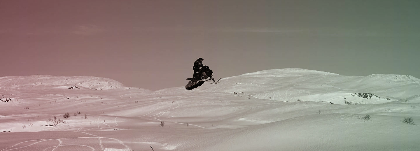 Snowmobile rider in a snowy and icy environment jumping