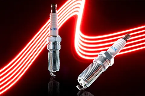 Two iridium spark plugs on a black background with a red lightning