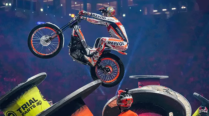 a motorcross rider jumping over obstacles  in an indoor venue
