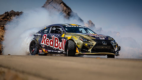 A Lexus drifting in a sandy and rocky environment