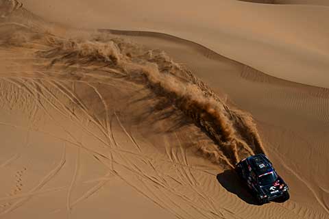 Rally car in the desert pictured from bird perspective